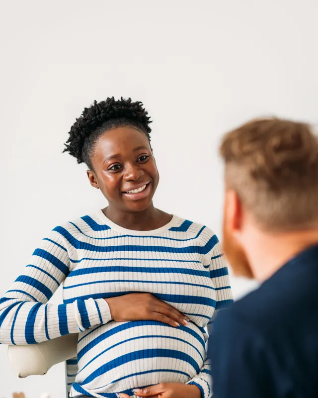 A pregnant woman smiling as she talks with her doctor