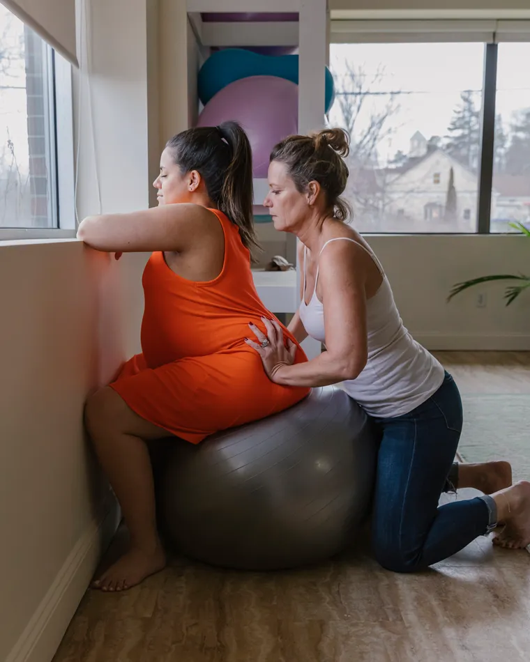 A doula supporting a woman on a birth ball
