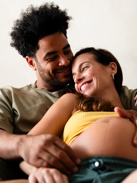 A couple laughing together with a hand on her belly